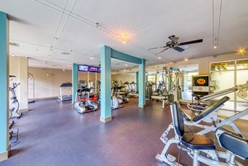 A gym with a variety of equipment including treadmills, weights, and exercise machines.